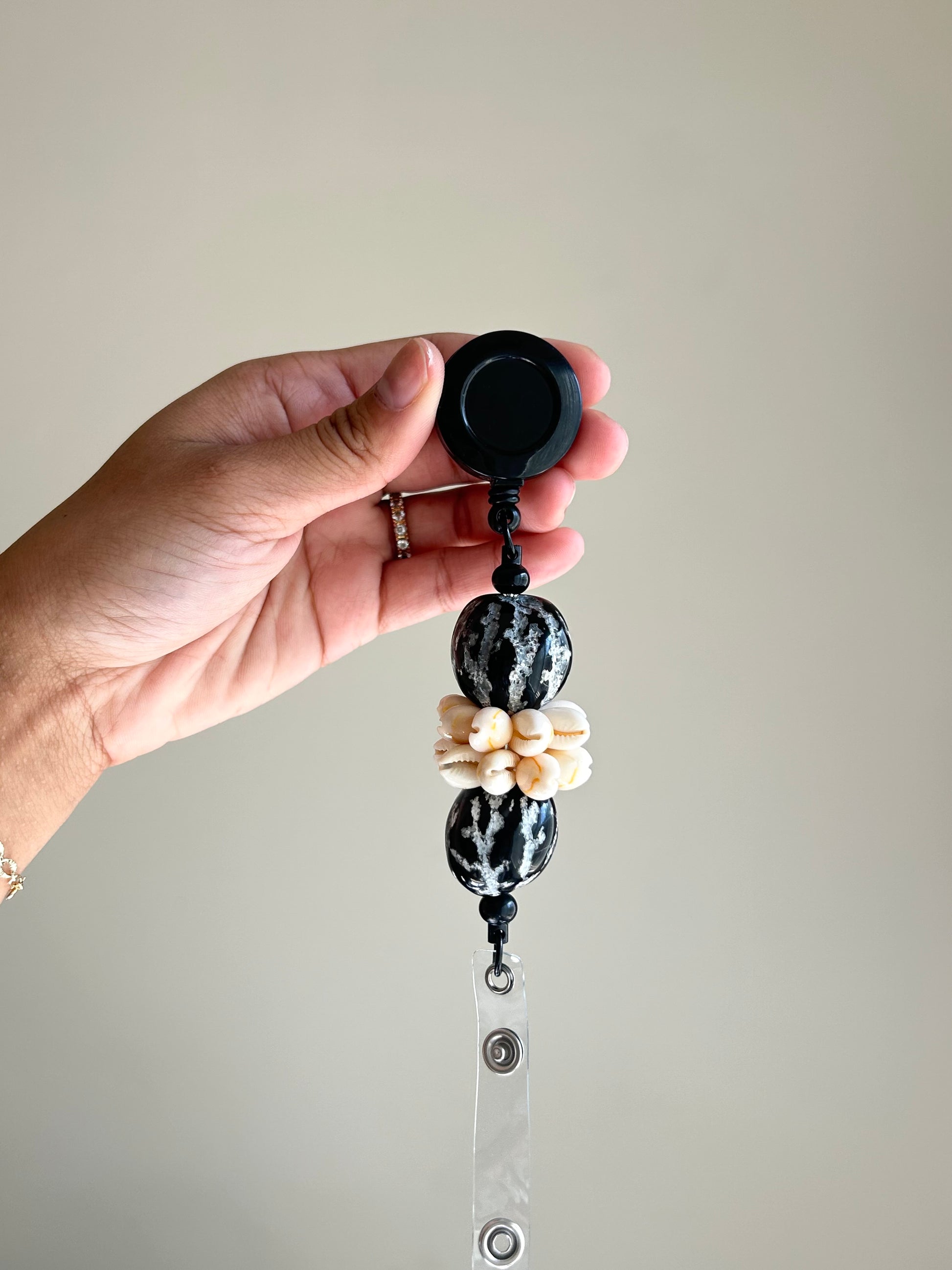Black kukui nut and cowrie shell badge reel with retractable clip and ID holder.
