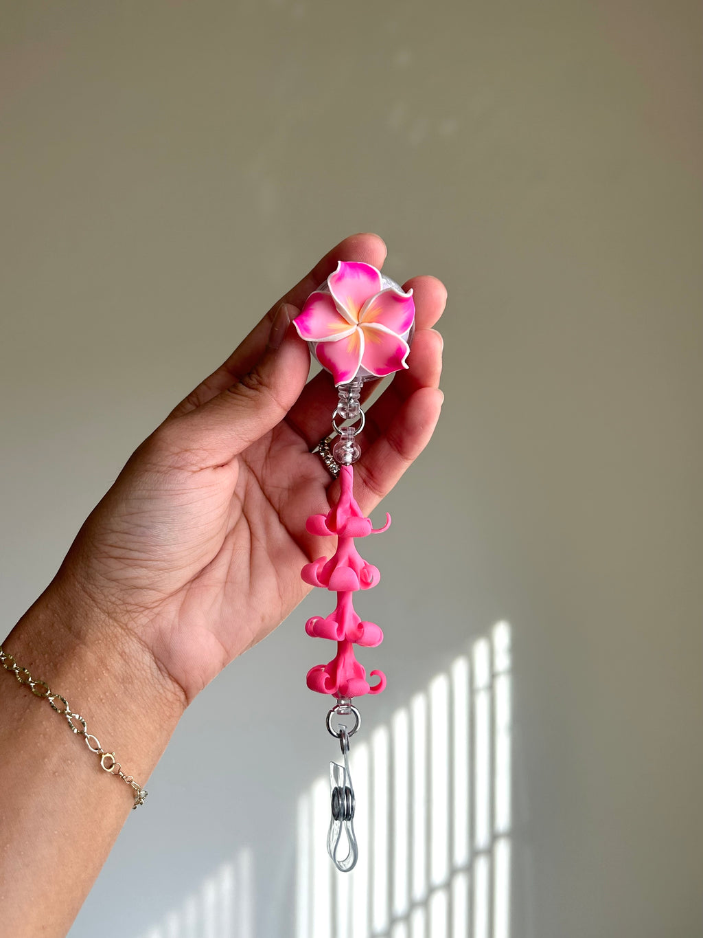 Pink plumeria and puakenikeni floral badge reel with retractable clip