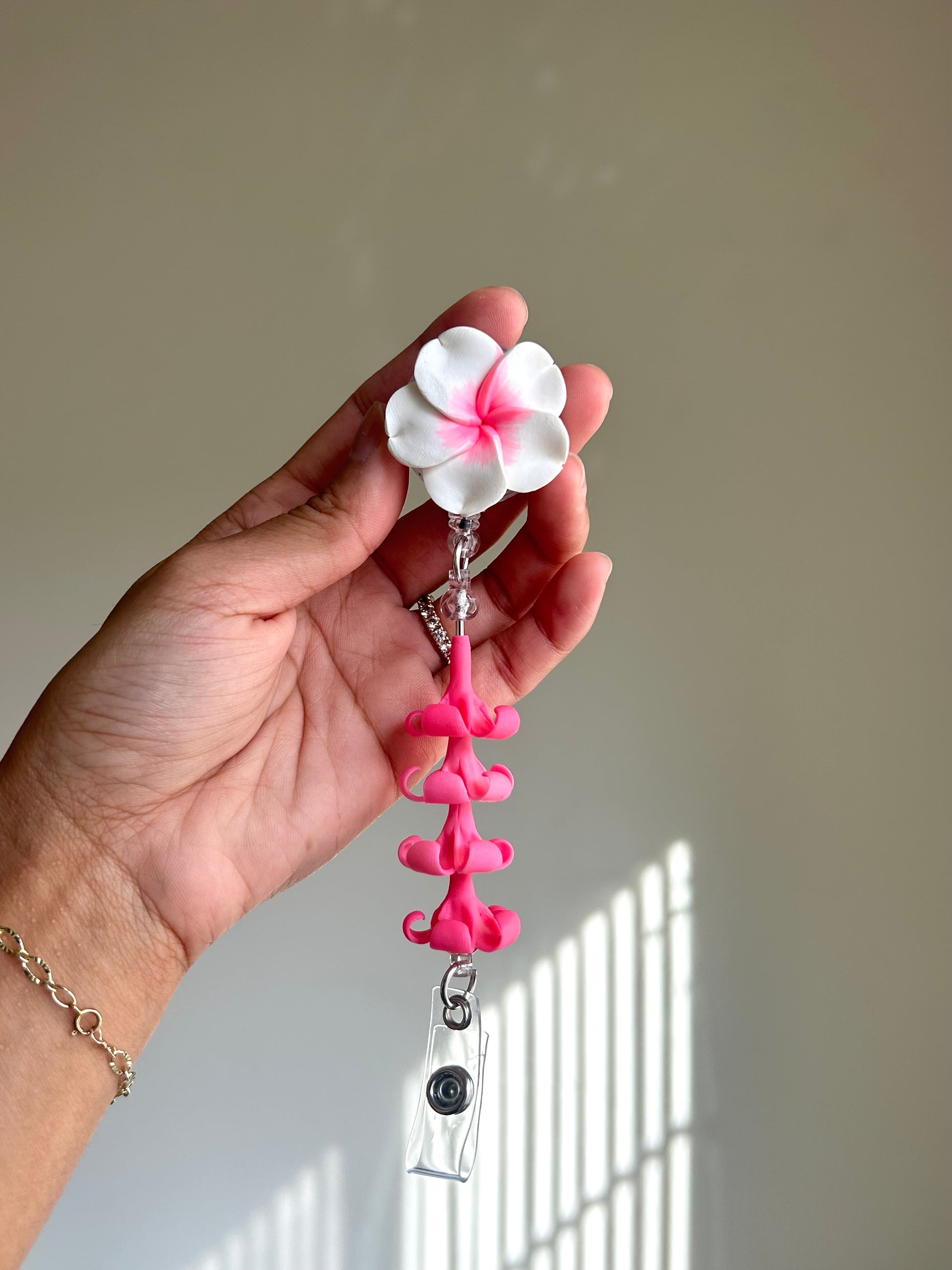 Pink plumeria and puakenikeni floral badge reel with retractable clip