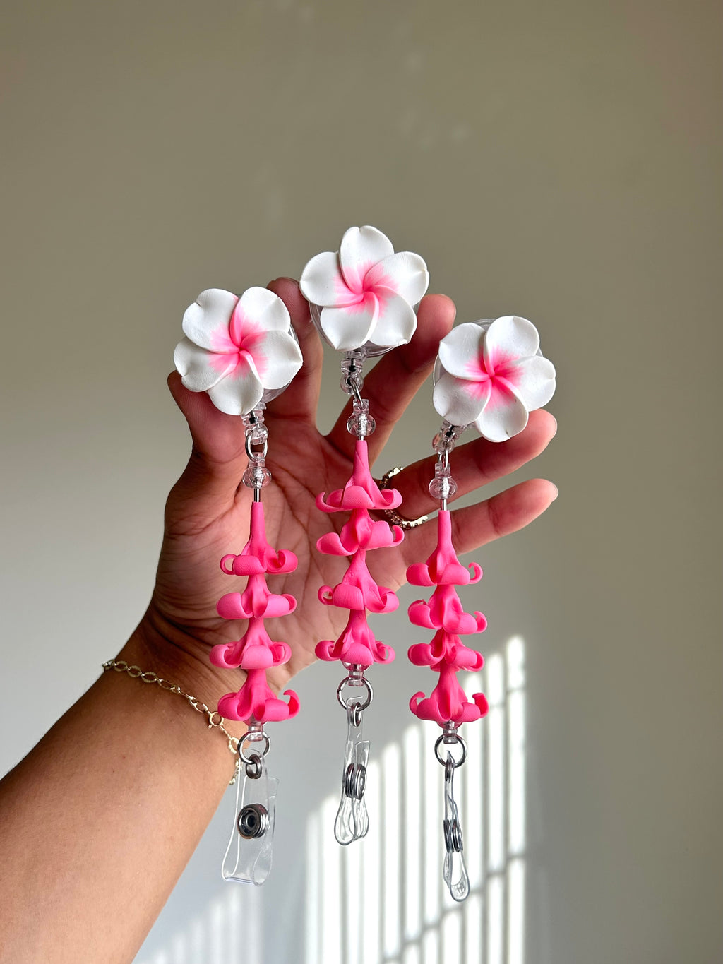 Pink plumeria and puakenikeni floral badge reel with retractable clip