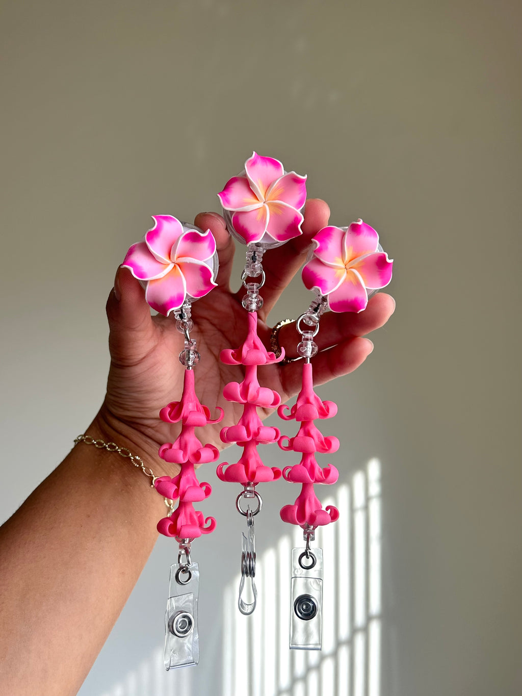 Pink plumeria and puakenikeni floral badge reel with retractable clip