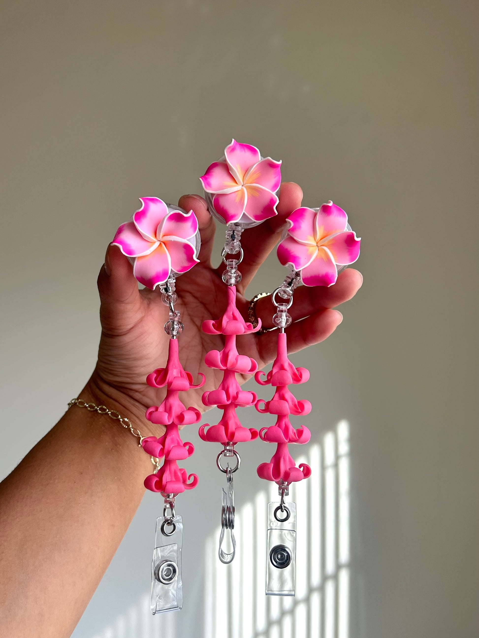 Pink plumeria and puakenikeni floral badge reel with retractable clip