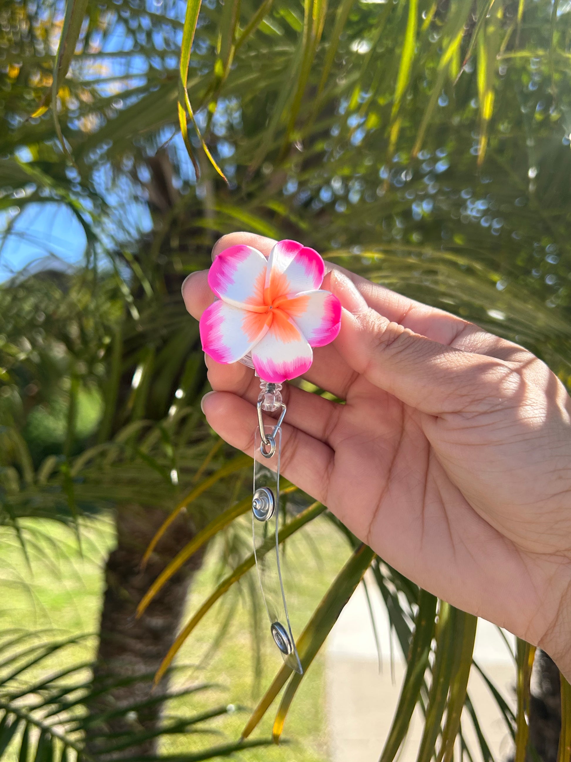 Pink plumeria floral badge reel with retractable clip