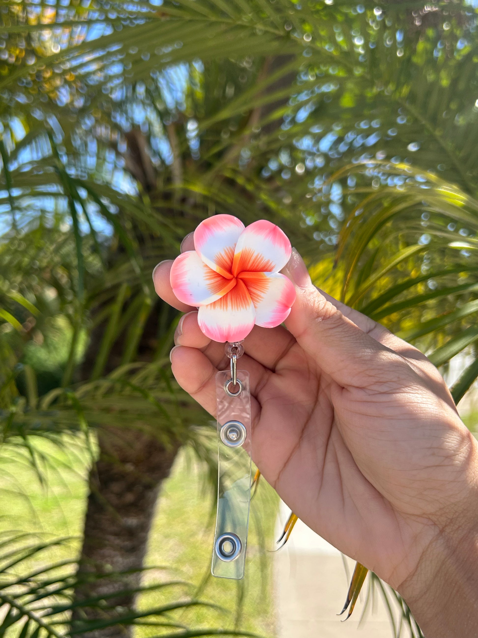 Pink and orange plumeria floral badge reel with retractable clip