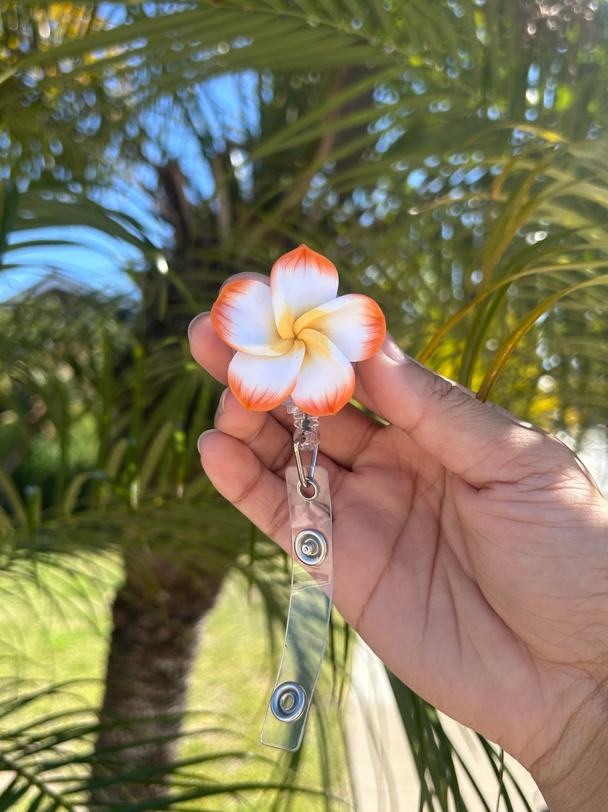 Orange and yellow plumeria floral badge reel with retractable clip