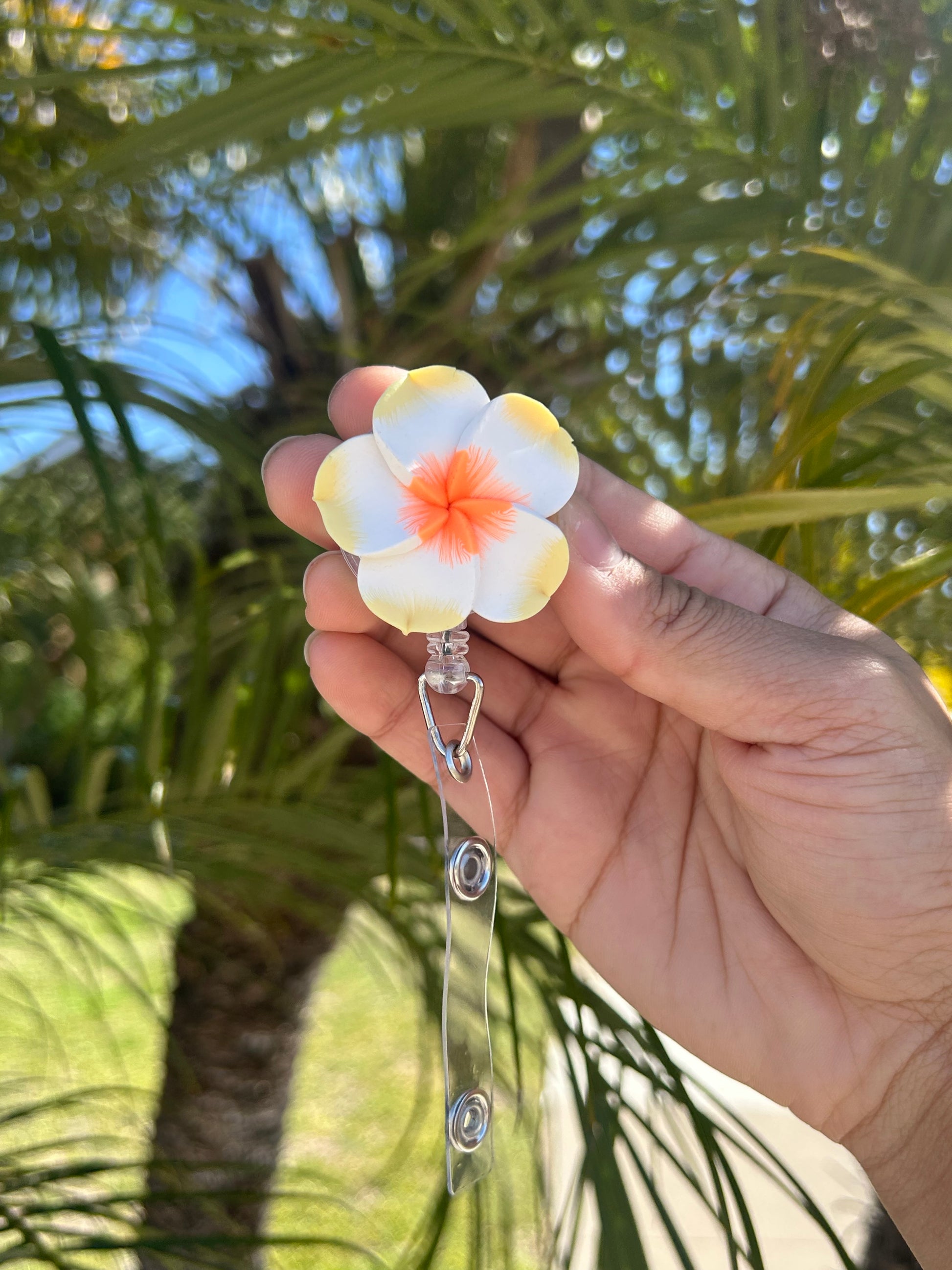 Yellow and orange plumeria floral badge reel with retractable clip