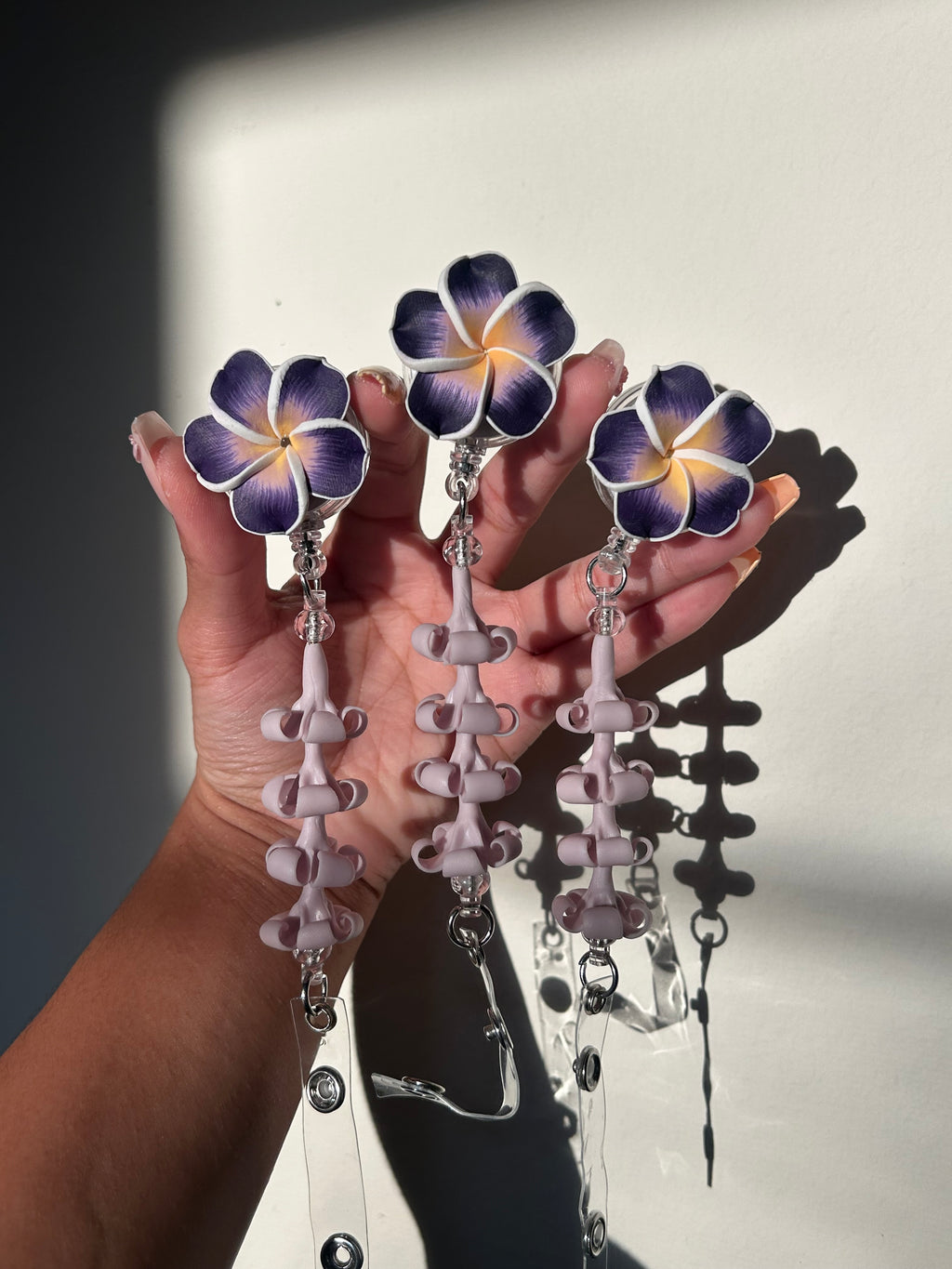 Purple lumeria and purple puakenikeni floral badge reel with retractable clip