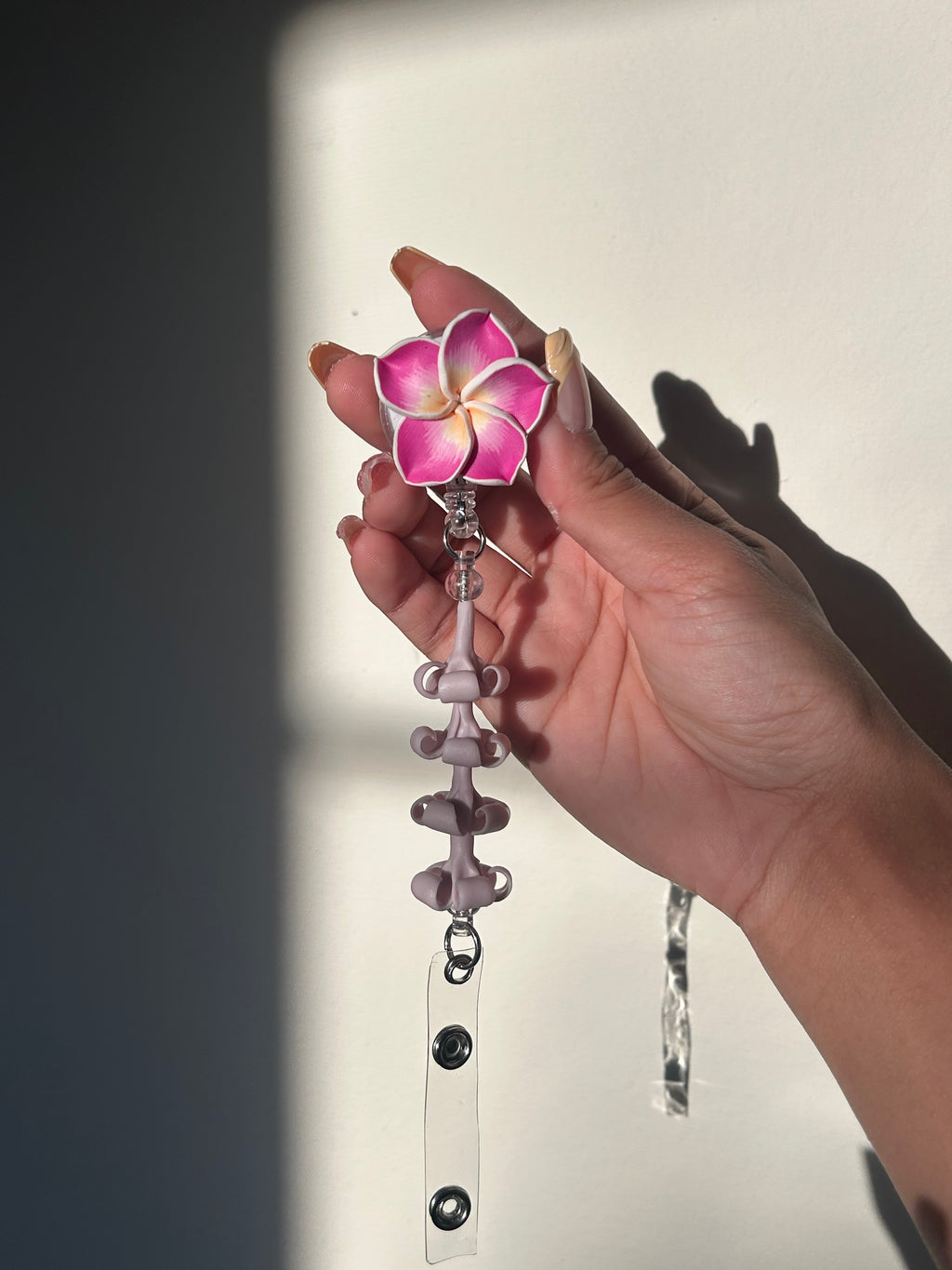 Purple lumeria and purple puakenikeni floral badge reel with retractable clip