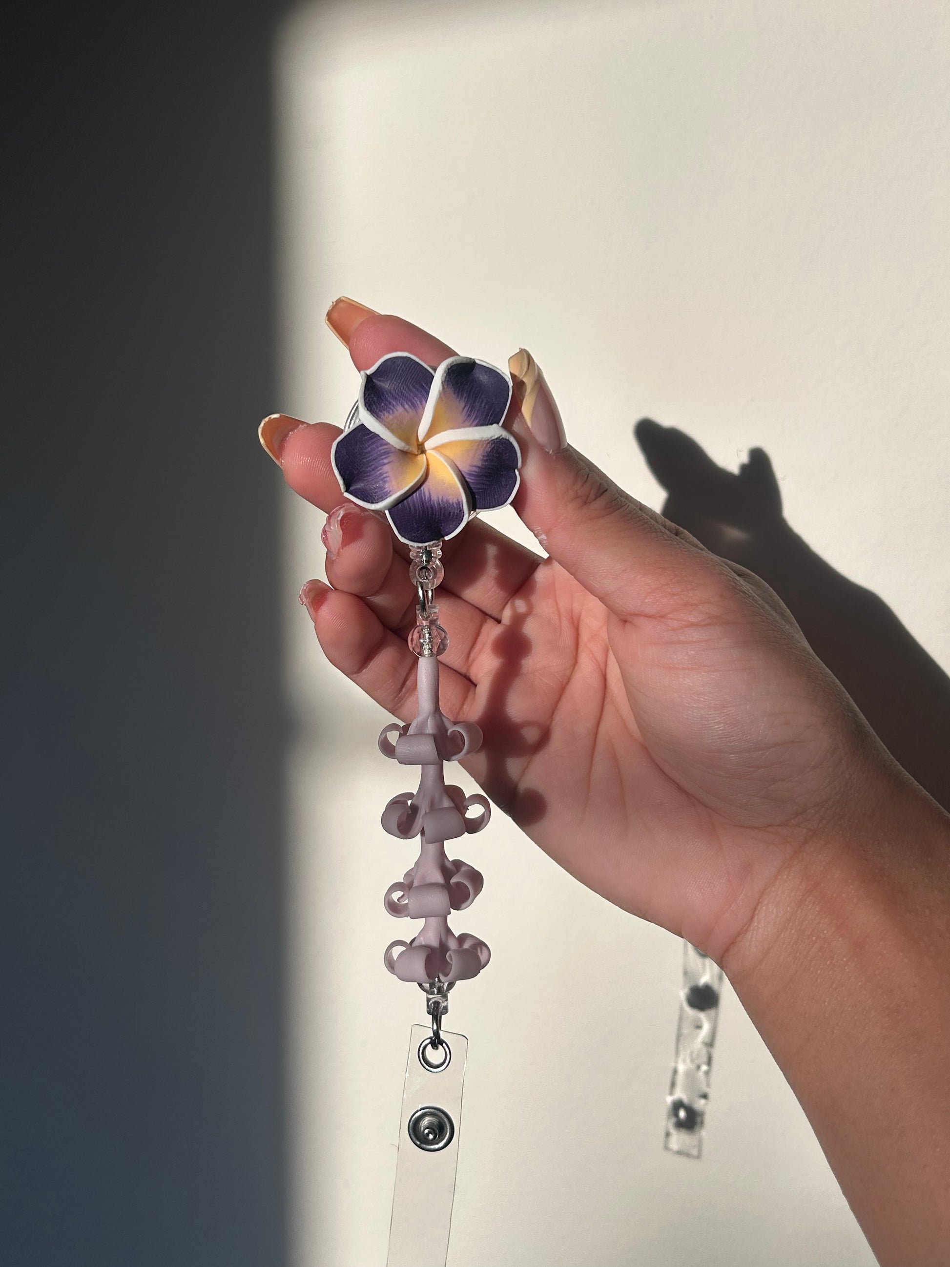 Purple lumeria and purple puakenikeni floral badge reel with retractable clip