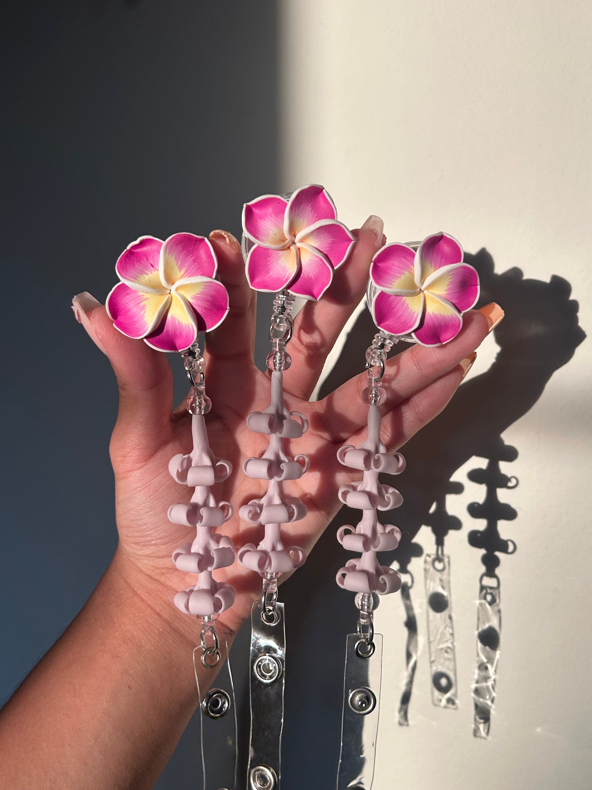 Purple lumeria and purple puakenikeni floral badge reel with retractable clip